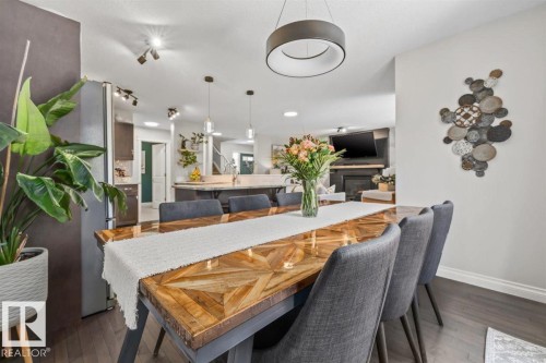 Dining area featuring dark wood-finish flooring, a unique wood-finish dining table, and a contemporary circular pendant light - 14 Edinburgh Crt N, St. Albert, AB 