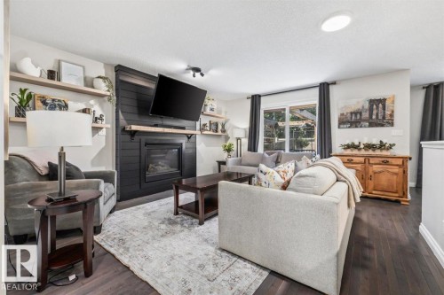 Living area featuring a dark wood-finish floor and a central fireplace with a dark shiplap surround and light wood mantel - 14 Edinburgh Crt N, St. Albert, AB 