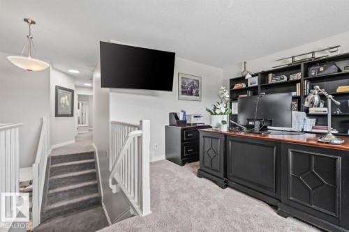 Versatile loft area featuring a built-in shelving unit, neutral carpeting, and white painted railings - 14 Edinburgh Crt N, St. Albert, AB 