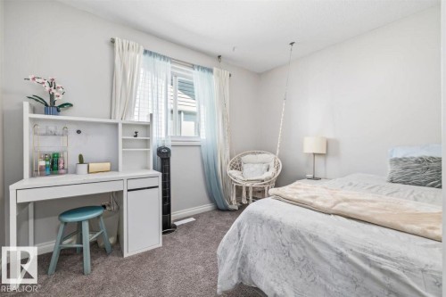 Carpeted bedroom featuring neutral wall tones, a window with natural light, and a built-in desk with shelving - 14 Edinburgh Crt N, St. Albert, AB 