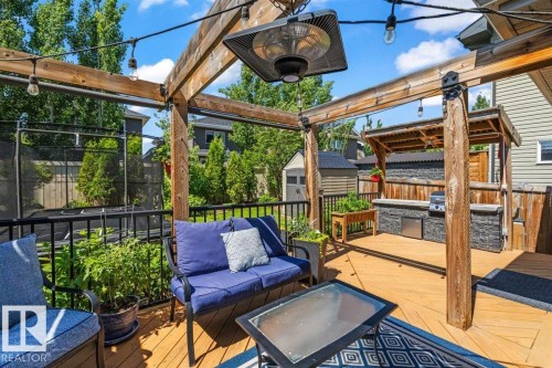 Wood-tone decking with a substantial pergola featuring string lighting and an overhead heater - 14 Edinburgh Crt N, St. Albert, AB 