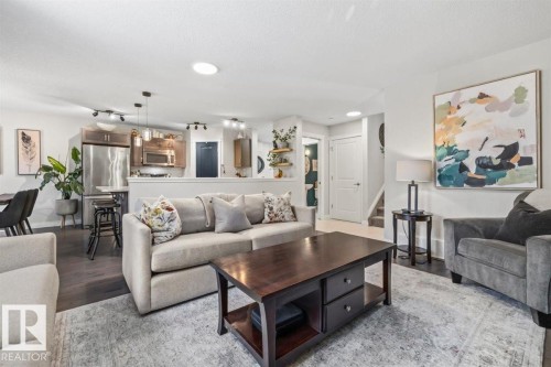 Open-concept living area featuring dark wood-finish flooring, recessed lighting, and a kitchen with stainless steel appliances and pendant lighting - 14 Edinburgh Crt N, St. Albert, AB 