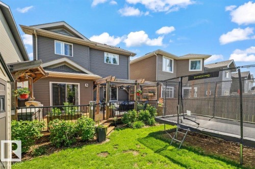 Rear exterior featuring a ground-level deck with wooden pergola, sliding glass door access, and a fully fenced yard with mature shrubs - 14 Edinburgh Crt N, St. Albert, AB 