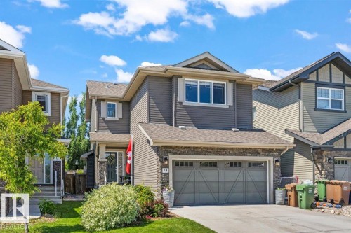 Two-story residence featuring a gray exterior with stone accents, an attached two-car garage, and a concrete driveway - 14 Edinburgh Crt N, St. Albert, AB 