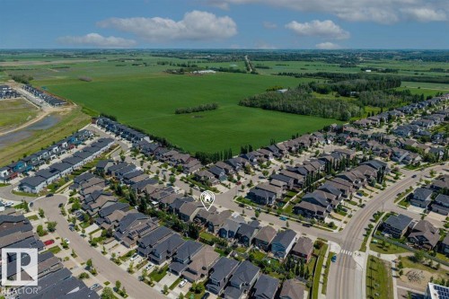 Aerial perspective showcasing a residential community bordered by expansive green fields and mature trees - 14 Edinburgh Crt N, St. Albert, AB 