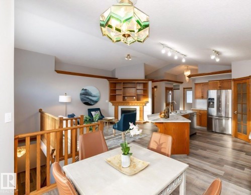Open-concept living space featuring vaulted ceilings, wood-finish flooring, and a decorative chandelier - 49 Heritage Drive, St. Albert, AB 