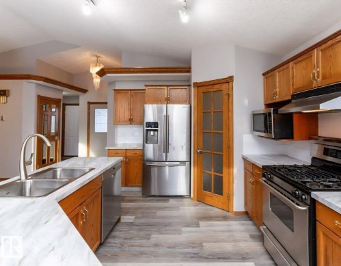 Kitchen featuring wood-finish cabinetry, stainless steel appliances, and wood-finish flooring - 49 Heritage Drive, St. Albert, AB 