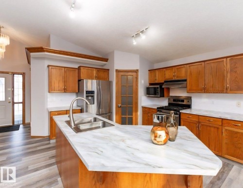 Kitchen featuring wood cabinetry, stainless steel appliances, and wood-finish flooring - 49 Heritage Drive, St. Albert, AB 