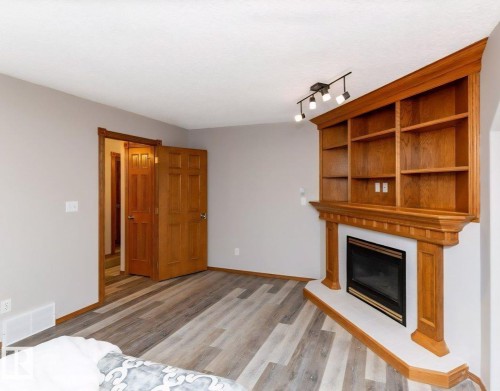 Integrated wood-finish shelving above a fireplace with a black insert and white hearth - 49 Heritage Drive, St. Albert, AB 