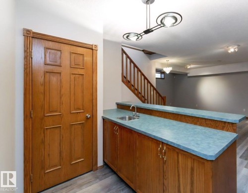 Wood-finish cabinetry with a built-in sink and light blue countertop - 49 Heritage Drive, St. Albert, AB 