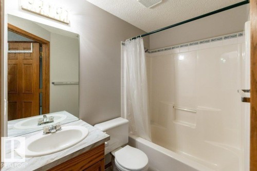 Bathroom featuring a vanity with a laminate countertop, an oval undermount sink, and a mirrored wall - 49 Heritage Drive, St. Albert, AB 