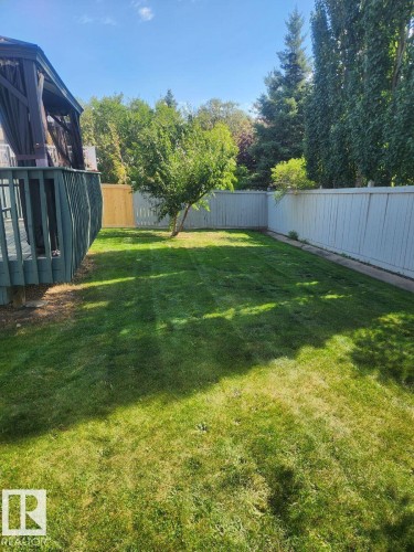 Expansive grassy yard with full fencing, mature trees, and a private deck featuring a covered gazebo - 49 Heritage Drive, St. Albert, AB 