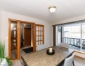 Dining area with wood-finish flooring, a large window with sliding door access, and a wood-framed glass-paneled door - 49 Heritage Drive, St. Albert, AB 