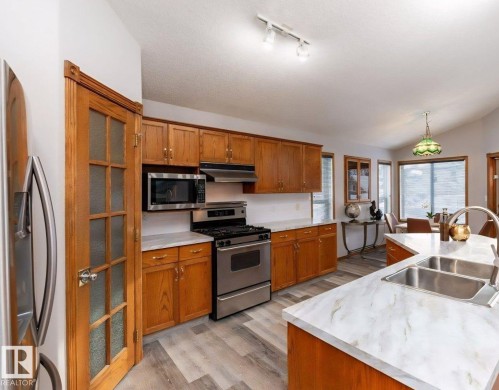 Kitchen featuring wood-finish cabinetry, stainless steel appliances, and light-toned countertops - 49 Heritage Drive, St. Albert, AB 