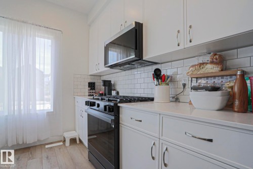 Kitchen featuring white cabinetry, subway tile backsplash, and light-toned countertops - 33 Eton Link, Spruce Grove, AB 