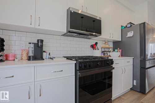 Modern kitchen featuring white shaker-style cabinetry with brushed nickel hardware, a white subway tile backsplash, and light-toned countertops - 33 Eton Link, Spruce Grove, AB 