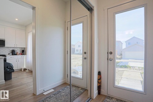 Entryway featuring wood-finish flooring, a full-length mirrored closet door, and a glass-paned exterior door - 33 Eton Link, Spruce Grove, AB 