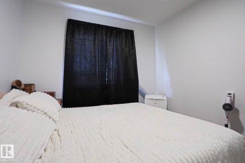 Bedroom featuring light-toned walls and a window with dark drapery - 33 Eton Link, Spruce Grove, AB 