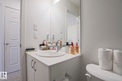White vanity with an integrated sink, polished chrome faucet, and a large wall-mounted mirror - 33 Eton Link, Spruce Grove, AB 