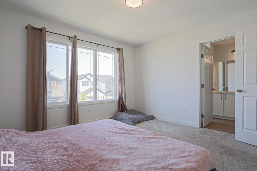 Bedroom featuring a large window, neutral carpeting, and a built-in overhead light fixture - 33 Eton Link, Spruce Grove, AB 