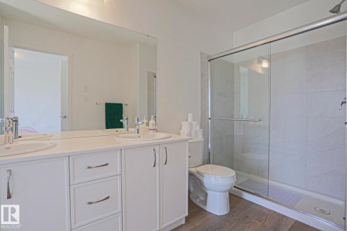 Modern bathroom featuring a double vanity with white cabinetry, integrated sinks, and polished chrome fixtures - 33 Eton Link, Spruce Grove, AB 