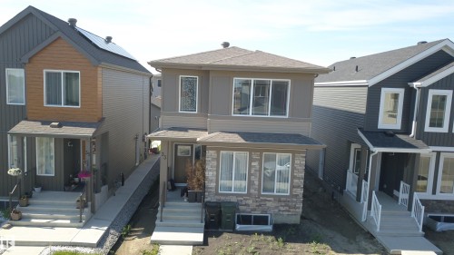 Two-story residence featuring a stone and siding facade, a covered front entry, and multiple windows - 33 Eton Link, Spruce Grove, AB 