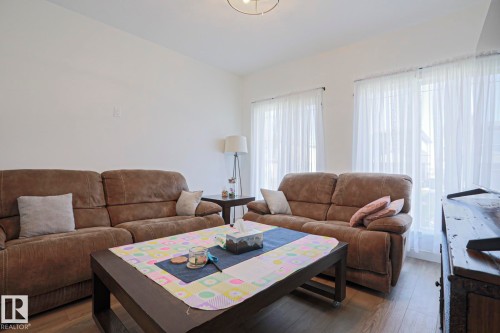 Bright living space featuring wood-finish flooring, white walls, and a ceiling-mounted light fixture - 33 Eton Link, Spruce Grove, AB 