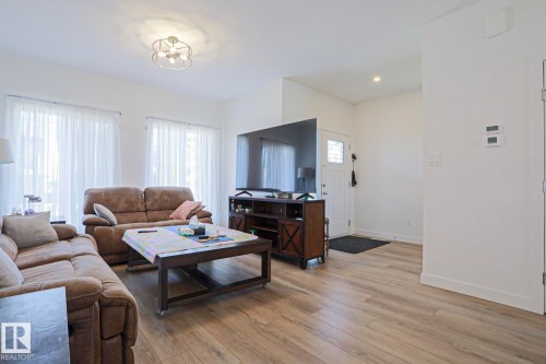 Open-concept living space with light wood-finish flooring, recessed lighting, and a contemporary semi-flush mount ceiling fixture - 33 Eton Link, Spruce Grove, AB 