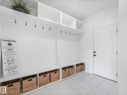 White built-in storage system with cubbies and hooks, featuring a bench seat and overhead shelving - 
