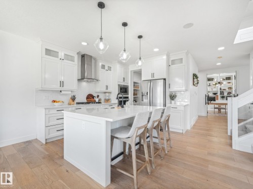 Contemporary kitchen featuring light wood-finish flooring and a large center island with seating - 5411 66 Street, Beaumont, AB 