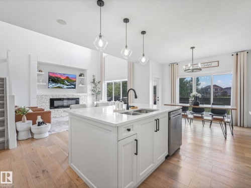 Central kitchen island with a double sink, stainless steel dishwasher, and pendant lighting - 5411 66 Street, Beaumont, AB 