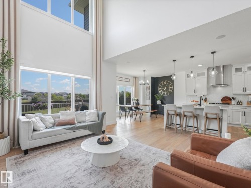 Open-concept living area featuring high ceilings, wood-finish flooring, and large windows - 5411 66 Street, Beaumont, AB 