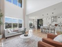 Open-concept living area featuring high ceilings, wood-finish flooring, and large windows - 5411 66 Street, Beaumont, AB 