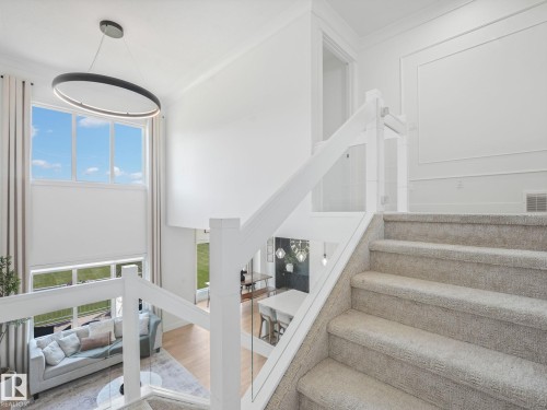 Carpeted staircase featuring a glass and white wood-finish railing - 5411 66 Street, Beaumont, AB 
