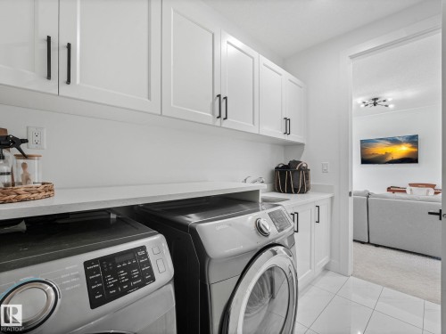 Laundry area featuring white shaker-style cabinetry, matte black hardware, and a light-toned countertop - 5411 66 Street, Beaumont, AB 