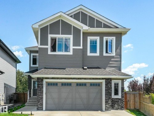 Contemporary two-story residence featuring grey siding, dark stone accents, and a grey shingle roof - 5411 66 Street, Beaumont, AB 