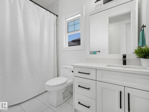 Bathroom featuring a white vanity with panel cabinetry and black hardware, a rectangular undermount sink with a matte black faucet, and a large framed mirror - 5411 66 Street, Beaumont, AB 