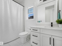 Bathroom featuring a white vanity with panel cabinetry and black hardware, a rectangular undermount sink with a matte black faucet, and a large framed mirror - 
