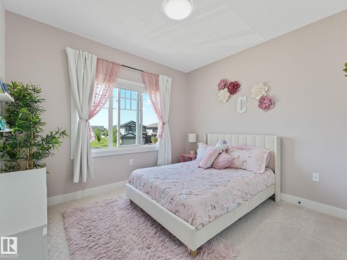 Bedroom featuring a large multi-pane window, wall-to-wall carpeting, and a ceiling-mounted light fixture - 5411 66 Street, Beaumont, AB 