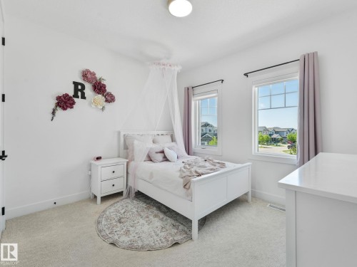 Bright room featuring two large windows, white walls, light-colored carpet, and a built-in ceiling light fixture - 5411 66 Street, Beaumont, AB 