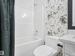 Bathroom featuring a white bathtub and shower combination with chrome fixtures - 