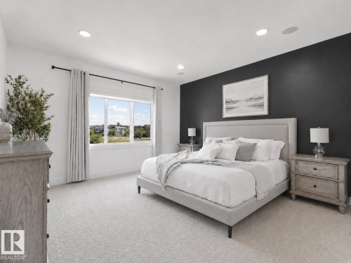 Spacious bedroom featuring light-colored carpeting, a large window with white trim, and a dark accent wall - 5411 66 Street, Beaumont, AB 