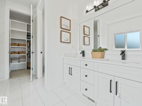 White double vanity with integrated sinks, black waterfall-style faucets, and quartz countertops - 5411 66 Street, Beaumont, AB 
