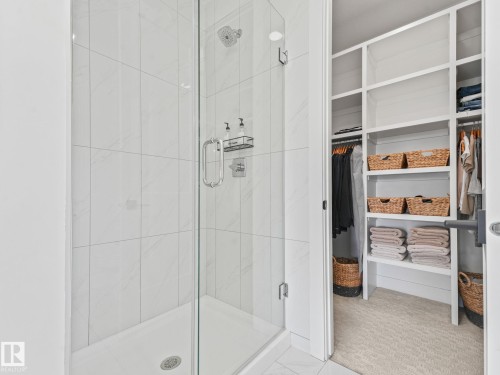 Glass-enclosed shower with a rainfall showerhead, tiled walls, and a built-in shower niche - 5411 66 Street, Beaumont, AB 