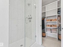 Glass-enclosed shower with a rainfall showerhead, tiled walls, and a built-in shower niche - 