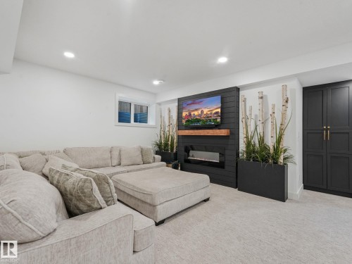 Contemporary living space featuring a shiplap accent wall with an electric fireplace and wood mantle - 5411 66 Street, Beaumont, AB 