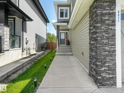 Contemporary exterior featuring stacked stone accents, horizontal siding, concrete walkway, and a covered entryway - 5411 66 Street, Beaumont, AB 
