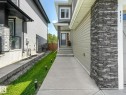 Contemporary exterior featuring stacked stone accents, horizontal siding, concrete walkway, and a covered entryway - 5411 66 Street, Beaumont, AB 