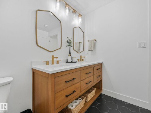 Dual vanity with light wood-finish cabinetry, white countertop, and gold-finish fixtures - 5411 66 Street, Beaumont, AB 