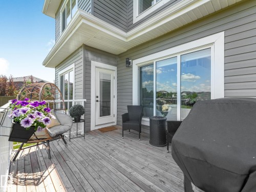 Expansive wood-finish deck with direct access to interior spaces through a glass-paneled door and sliding glass doors - 5411 66 Street, Beaumont, AB 